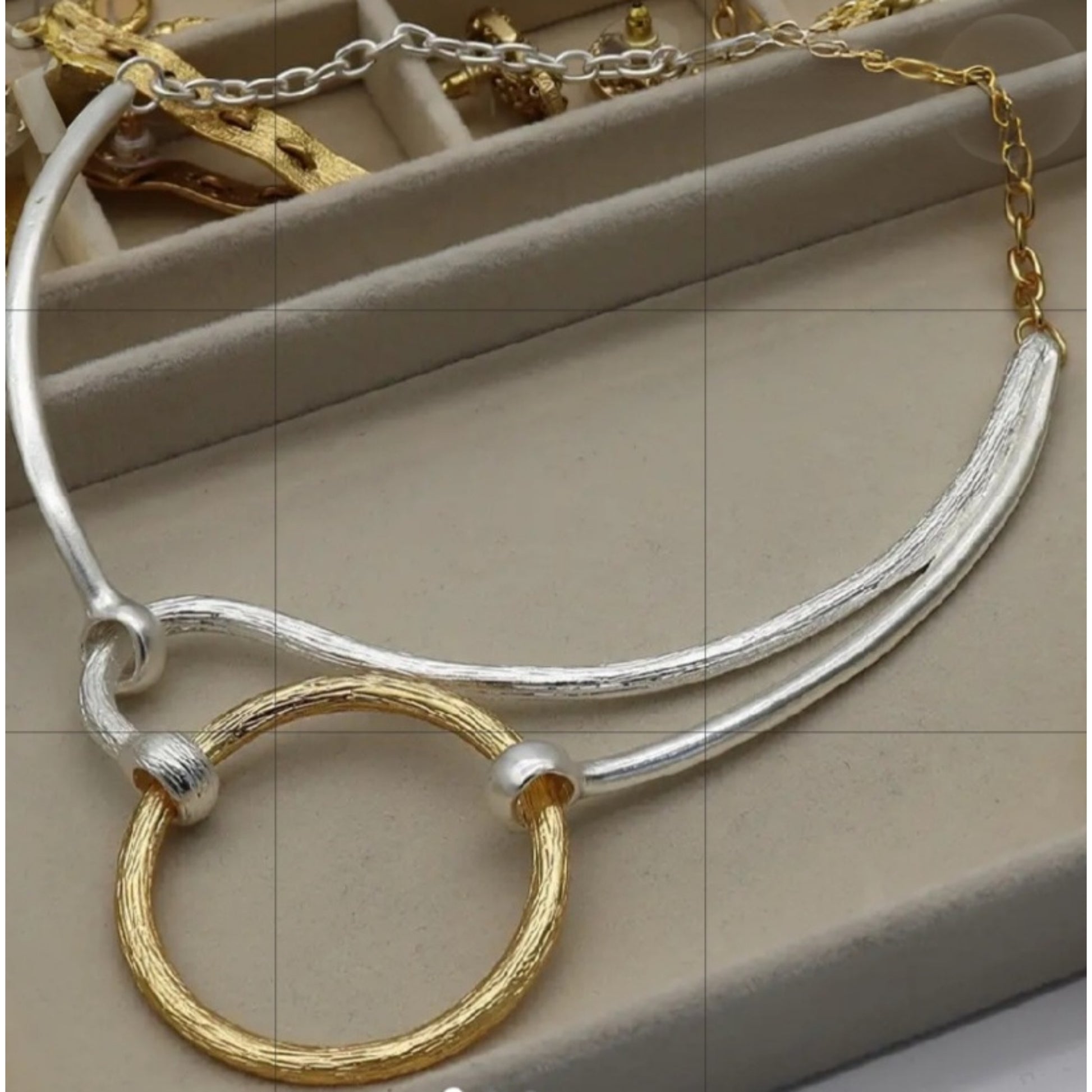 Silver and gold necklace on a beige surface