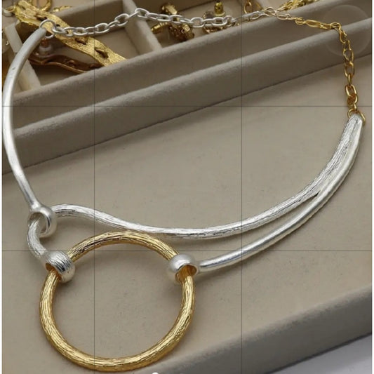 Silver and gold necklace on a beige surface