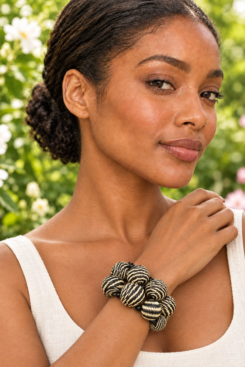 Woman wearing the cream-and-black Icara bracelet in a garden