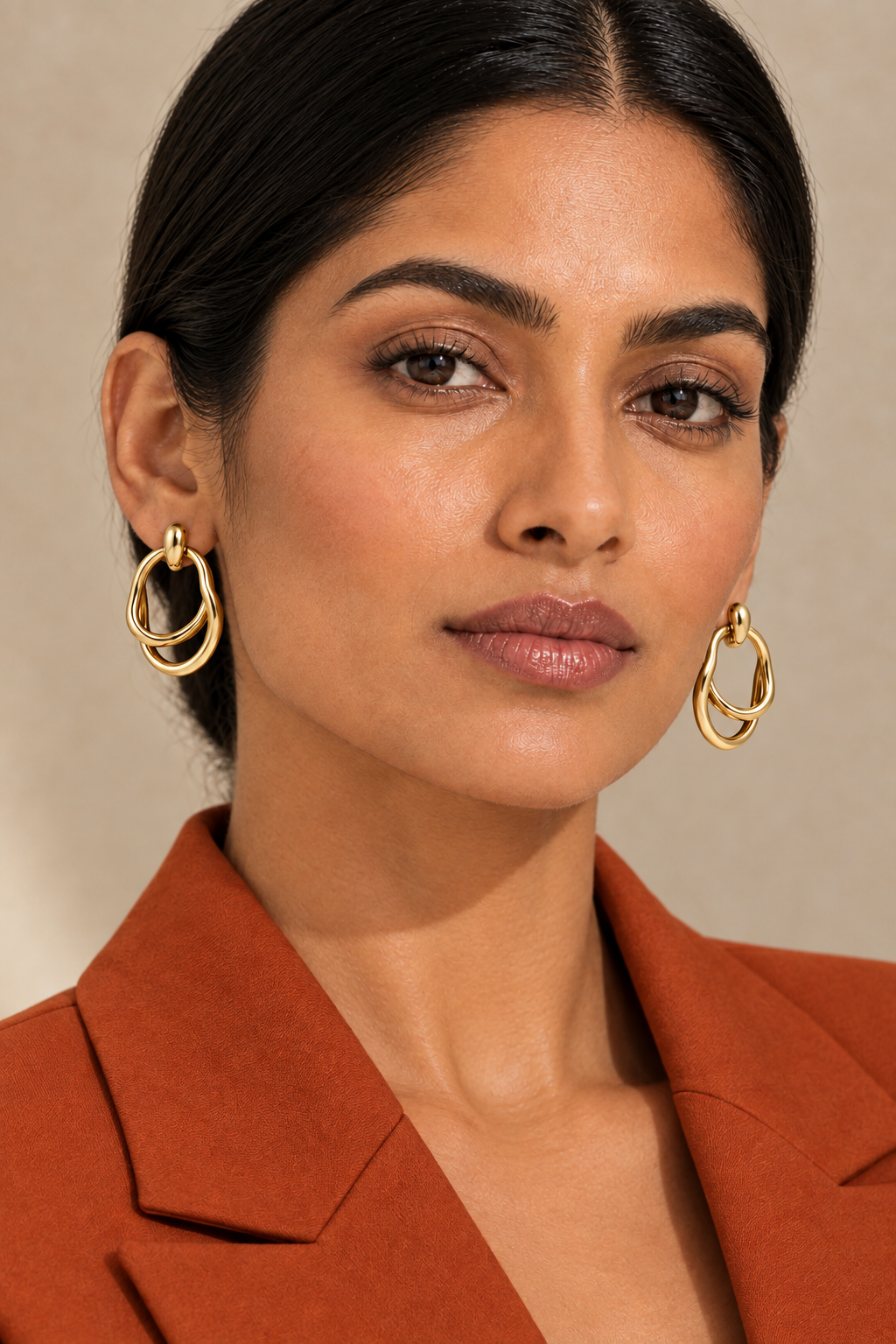 Closer portrait of the model in a burnt orange suit wearing the earrings