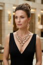 Elegant woman wearing the referenced jewelry set with a black V-neck dress in an upscale lounge