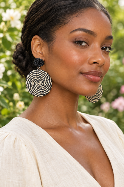 Woman in her twenties wearing black-and-cream woven earrings in a garden